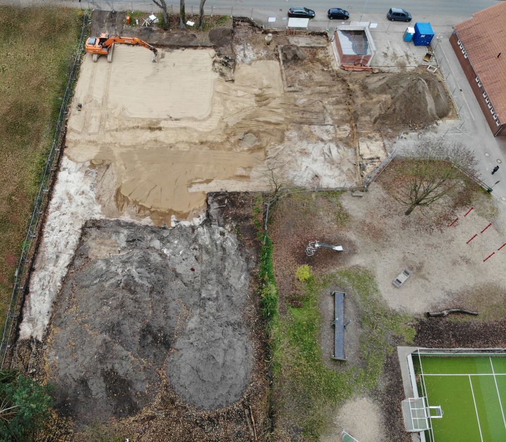 Das Luftbild zeigt die Baustelle des Feuerwehrgerätehauses am 23.11.2019. Ein Bagger verteilt Sand auf dem zukünftigen Bauplatz.