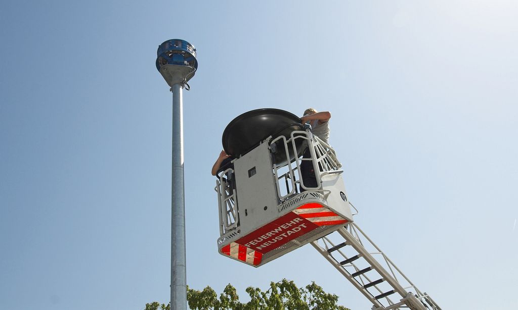 Das Foto zeigt, wie mit hoher Präzision der Drehleiterkorb so positioniert wird, dass die Schutzhaube aufgesetzt werden kann.
