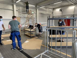 Reges Treiben: In der Fahrzeughalle sind Feuerwehrkameradinnen und -kameraden damit beschäftigt, die Regale, Schränke und weitere Ausstattungen auf- und einzubauen.