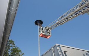 Die Aufnahme zeigt, dass der Drehleiterkorb neu positioniert werden musste, um auch die hintere Verschraubung der Schutzhaube zu erreichen.